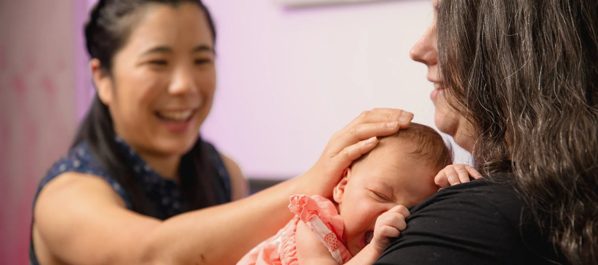 Mother holding newborn during postpartum clinic visit.