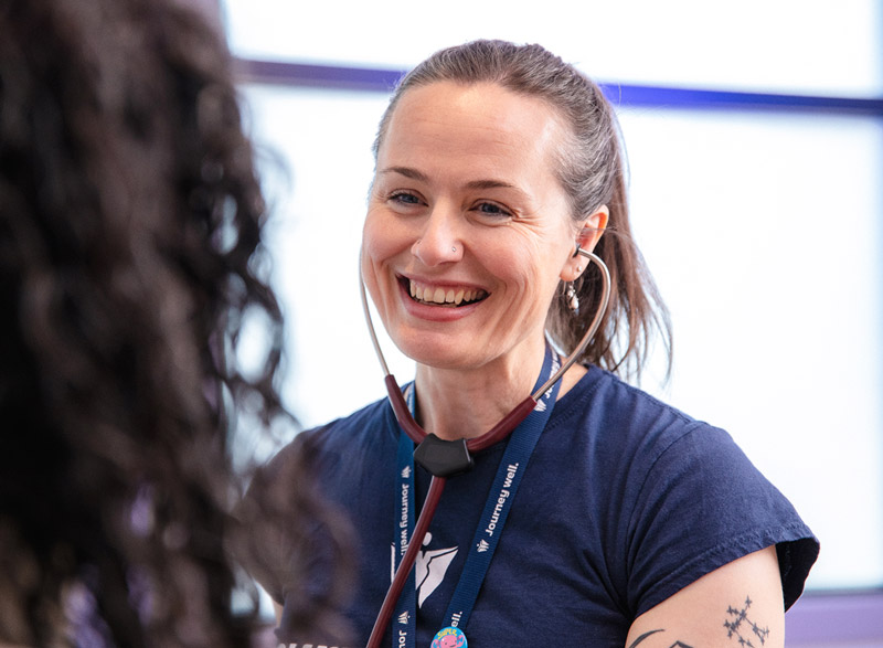 Smiling nurse wearing a stethoscope talks with a patient during an appointment.