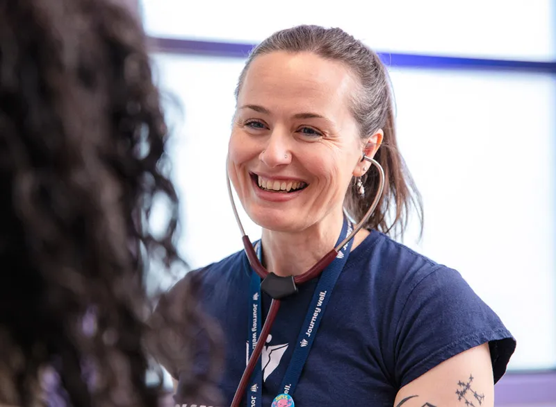 Nurse wearing stethoscope smiling during patient visit.