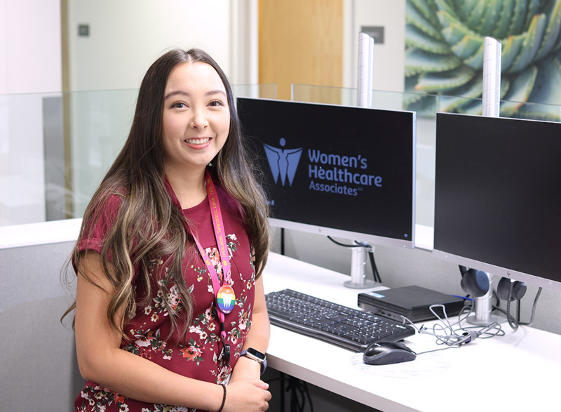 Patient services team member sits at the front desk workstation with Women’s Healthcare Associates logo on the computer screen.